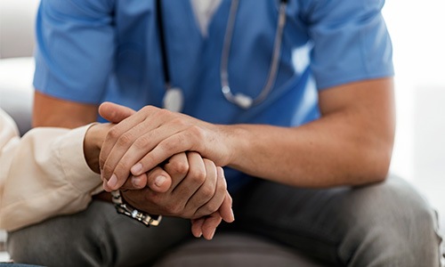 a nurse holding a patient's hand